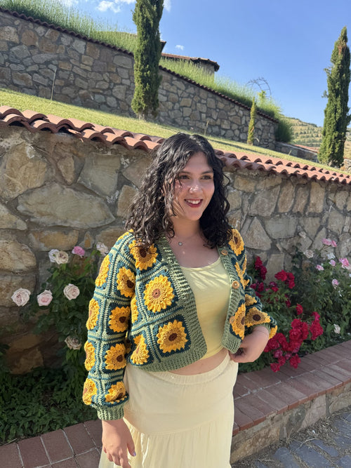 Customer in a sunflower crochet cardigan beside a stone wall