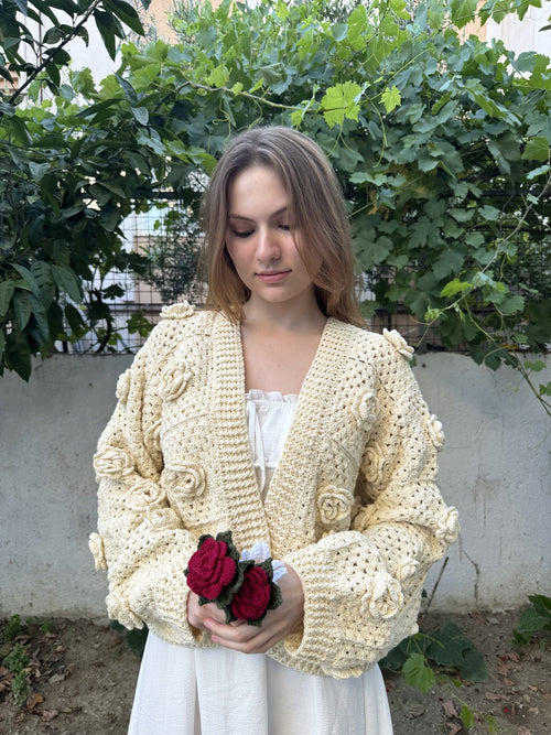 Customer in a cream hand-knitted cardigan holding crochet roses