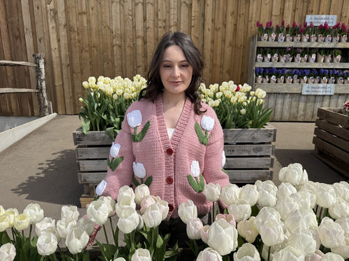 Customer in a pink tulip cardigan standing among white tulips