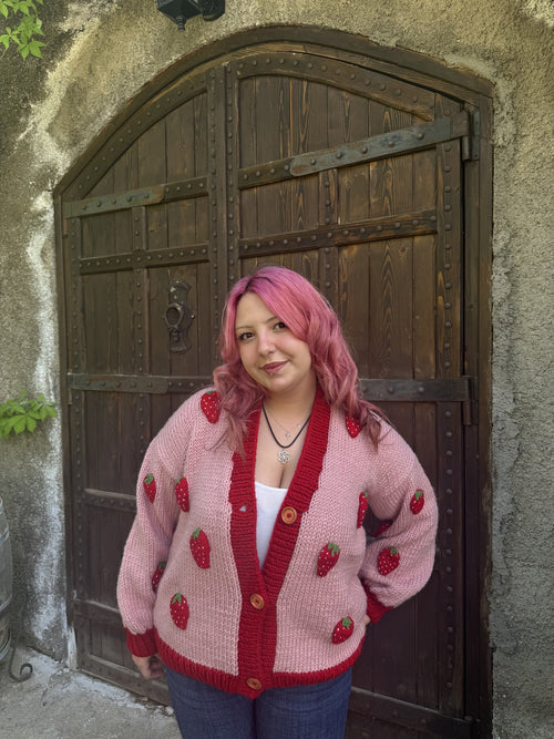 Customer in a pink strawberry cardigan by a wooden door