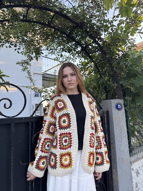 Customer in a cream granny-square cardigan by an iron gate