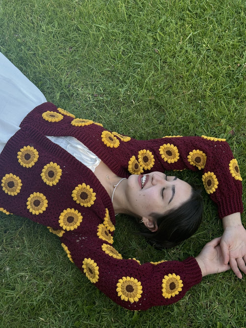 Customer lying on grass in a burgundy sunflower cardigan