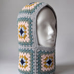 Teal and mustard granny square balaclava on a display head, open face and deep neck section — handmade by Ana Chic