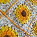 Close-up of a crocheted sunflower square with yellow puff-stitch petals on the cream shoulder bag — handmade by Ana Chic