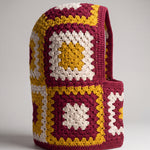 Burgundy and mustard granny square balaclava standing on its own, back view of the hood — handmade by Ana Chic