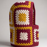 Burgundy and mustard granny square balaclava standing on its own, back view of the hood — handmade by Ana Chic
