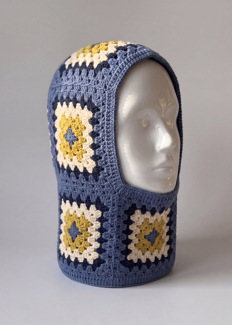 Denim blue and mustard granny square balaclava on a display head, open face and deep neck section — handmade by Ana Chic