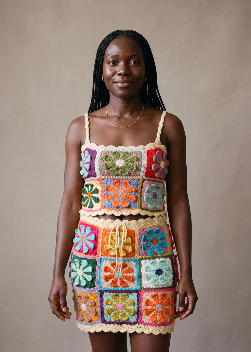Model wearing the Bloom Set — daisy granny-square crop top and matching mini skirt in multicolour crochet with pale cream scalloped trim, handmade by Ana Chic