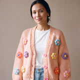 Woman wearing the Daisy Peach cardigan — peach chunky hand-knitted wool cardigan with pastel puff-stitch flowers over a white T-shirt, handmade by Ana Chic