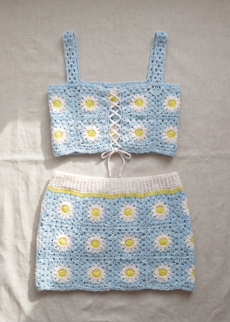 Pale blue crochet daisy top and skirt set laid flat on linen - handmade by Ana Chic
