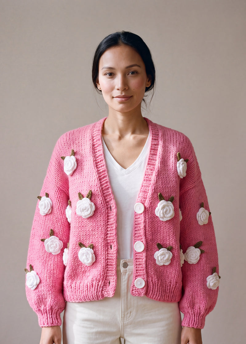 Woman wearing the Rose Bubblegum cardigan — bubblegum pink chunky hand-knitted wool cardigan with crocheted white roses over a white V-neck, handmade by Ana Chic