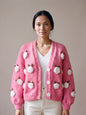 Woman wearing the Rose Bubblegum cardigan — bubblegum pink chunky hand-knitted wool cardigan with crocheted white roses over a white V-neck, handmade by Ana Chic