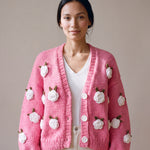 Woman wearing the Rose Bubblegum cardigan — bubblegum pink chunky hand-knitted wool cardigan with crocheted white roses over a white V-neck, handmade by Ana Chic