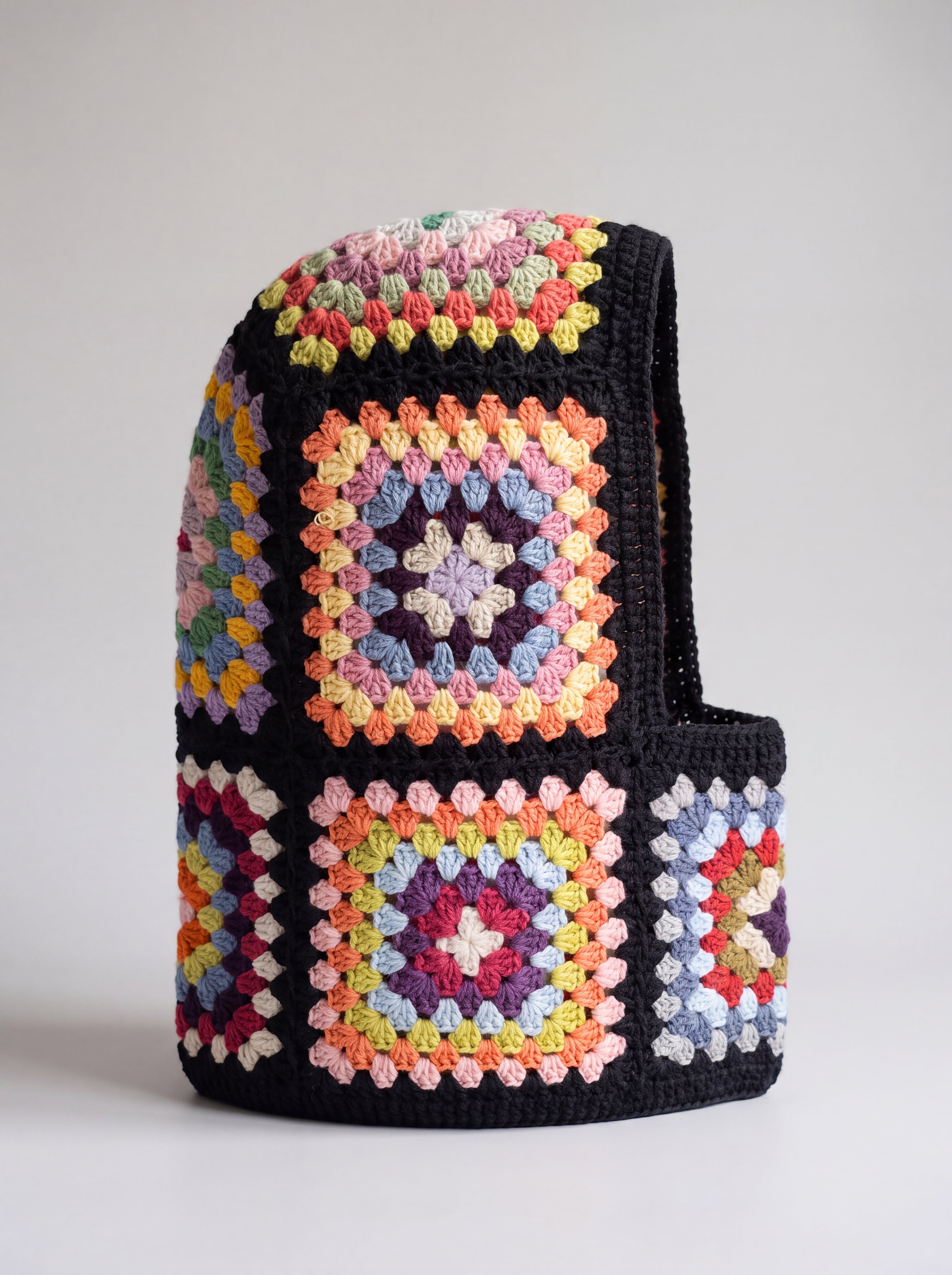 Black pastel granny square balaclava standing on its own, back view of the hood — handmade by Ana Chic