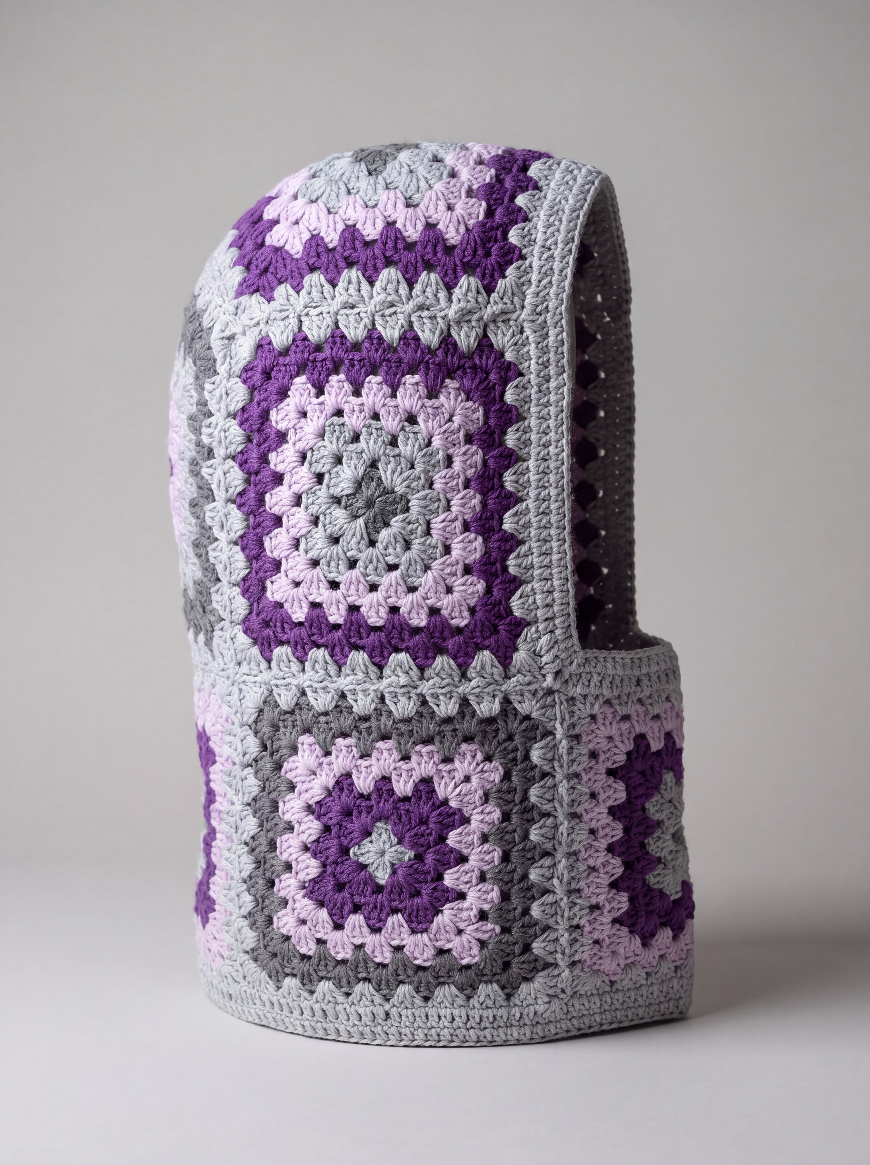 Grey and purple granny square balaclava standing on its own, back view of the hood — handmade by Ana Chic
