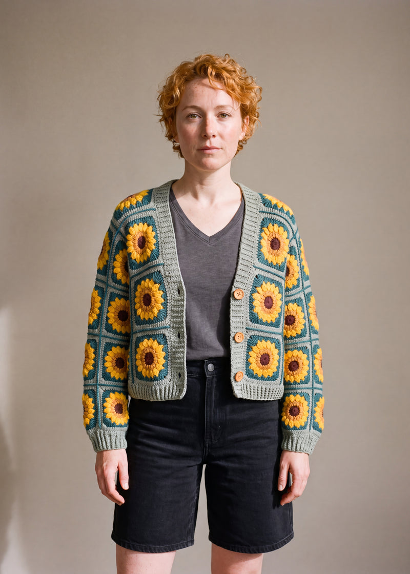 Crop Sunflower Cardigan - Sage and Teal - TWO ground colours alternating in a checker: sage green squares and deep teal squares. Same sunflower in both - brown centre crocheted granny square cardigan with raised crochet sunflowers, worn by Ana Chic