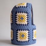 Denim blue and mustard granny square balaclava standing on its own, back view of the hood — handmade by Ana Chic