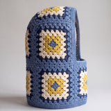 Denim blue and mustard granny square balaclava standing on its own, back view of the hood — handmade by Ana Chic