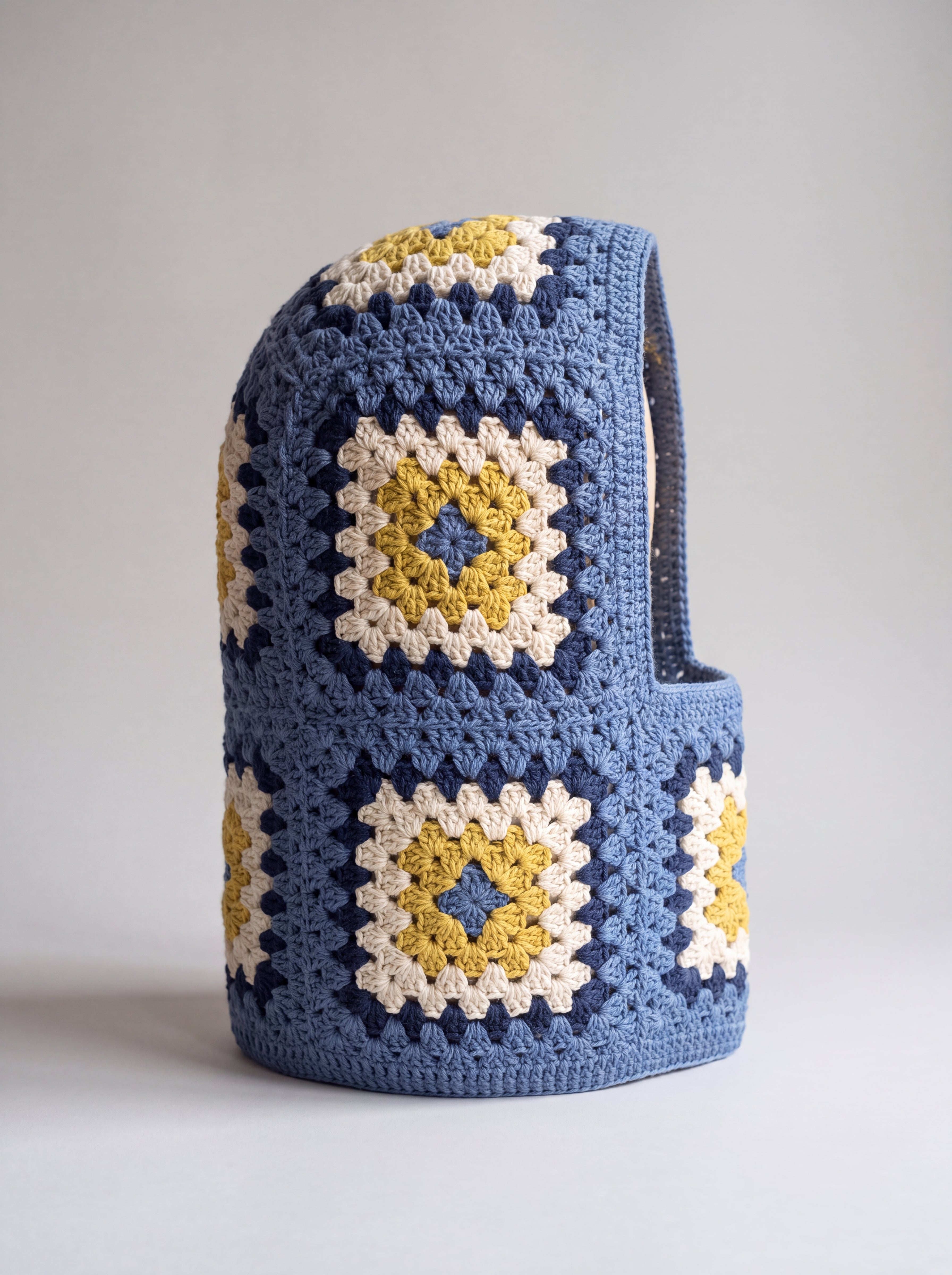 Denim blue and mustard granny square balaclava standing on its own, back view of the hood — handmade by Ana Chic