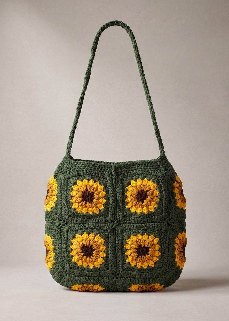 Front of the dark green crochet crossbody bag with four sunflower squares and a long braided strap — handmade by Ana Chic