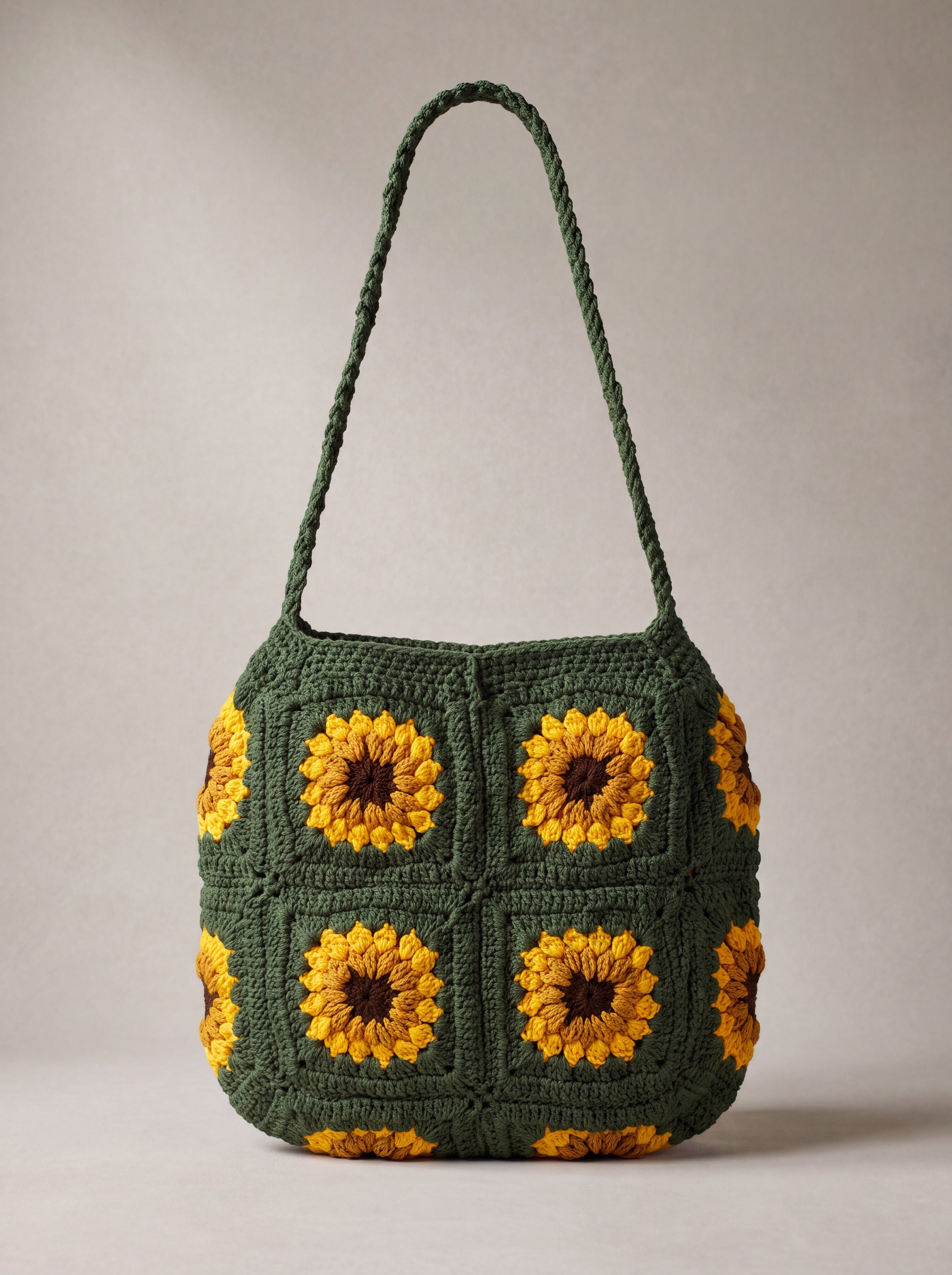 Front of the dark green crochet crossbody bag with four sunflower squares and a long braided strap — handmade by Ana Chic
