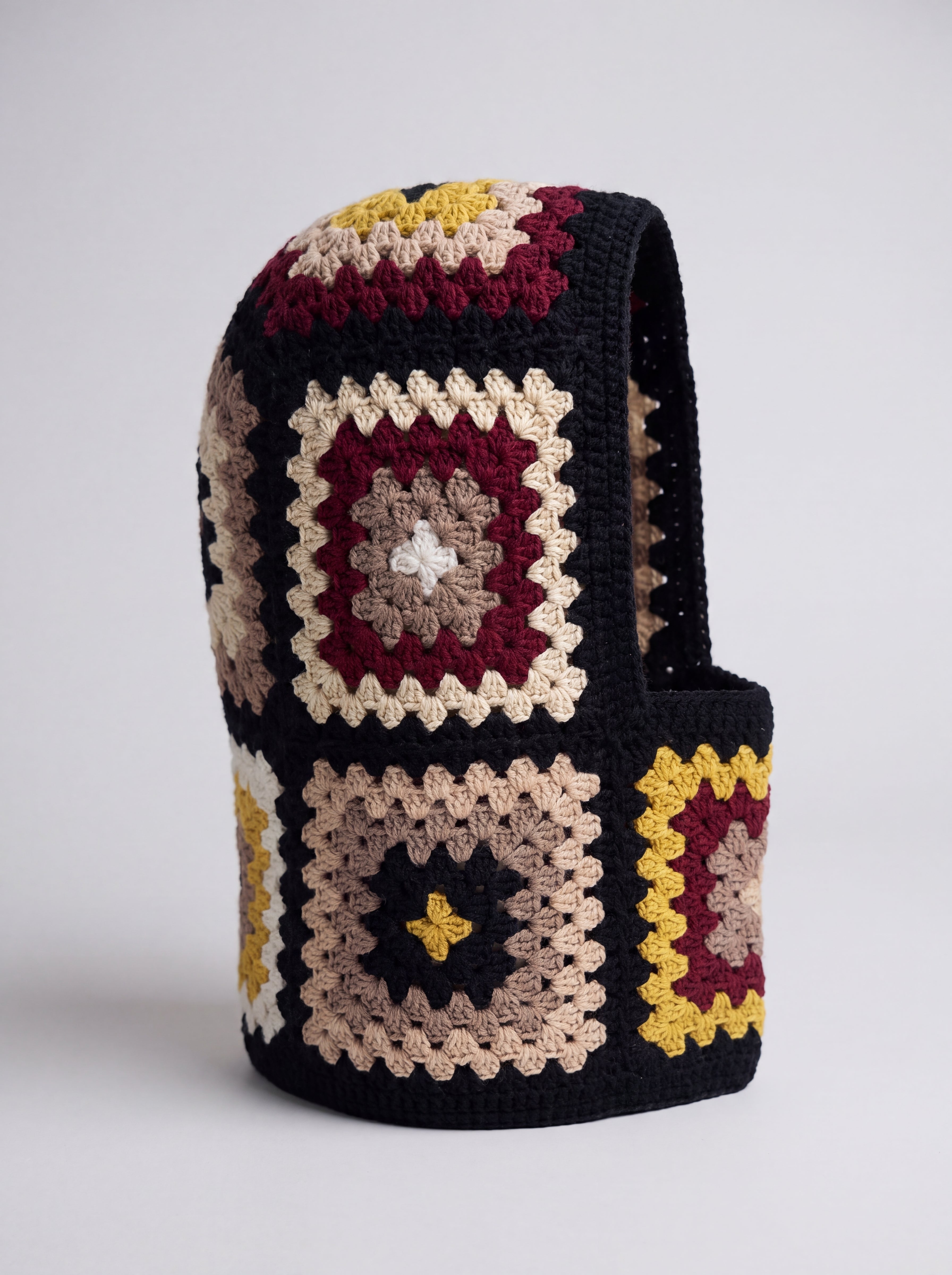Black and burgundy granny square balaclava standing on its own, back view of the hood — handmade by Ana Chic
