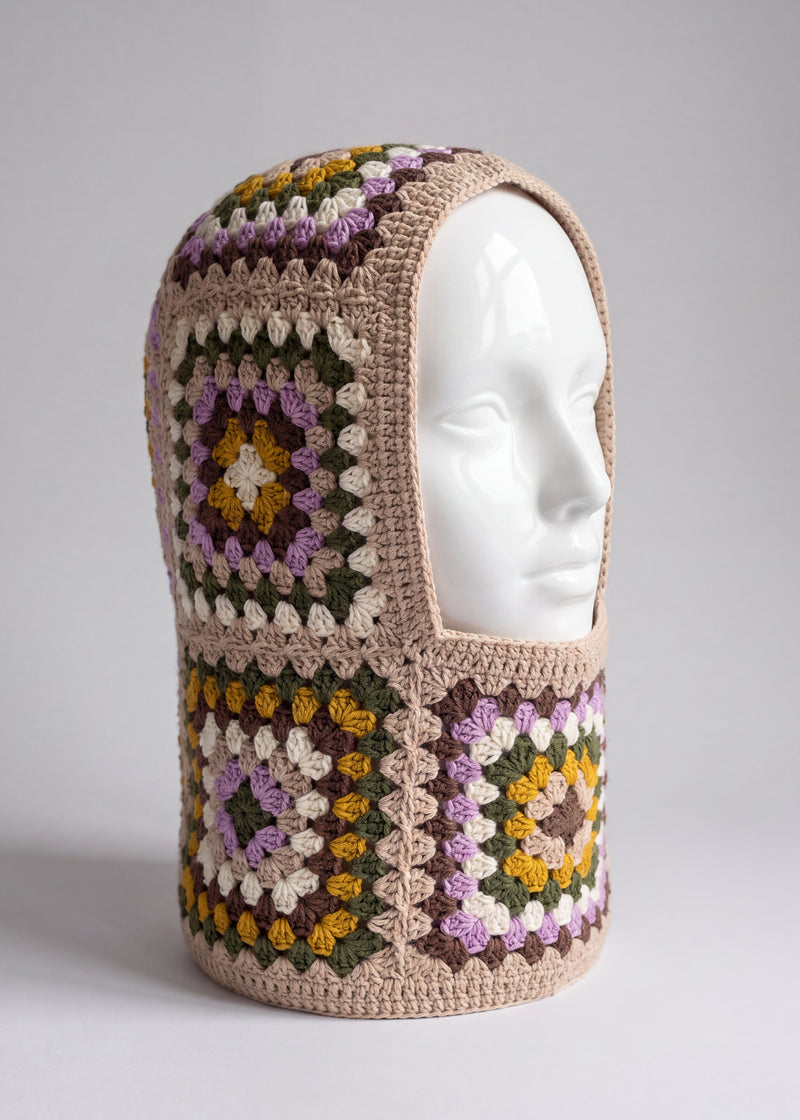 Sand and lilac granny square balaclava on a display head, open face and deep neck section — handmade by Ana Chic
