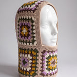 Sand and lilac granny square balaclava on a display head, open face and deep neck section — handmade by Ana Chic