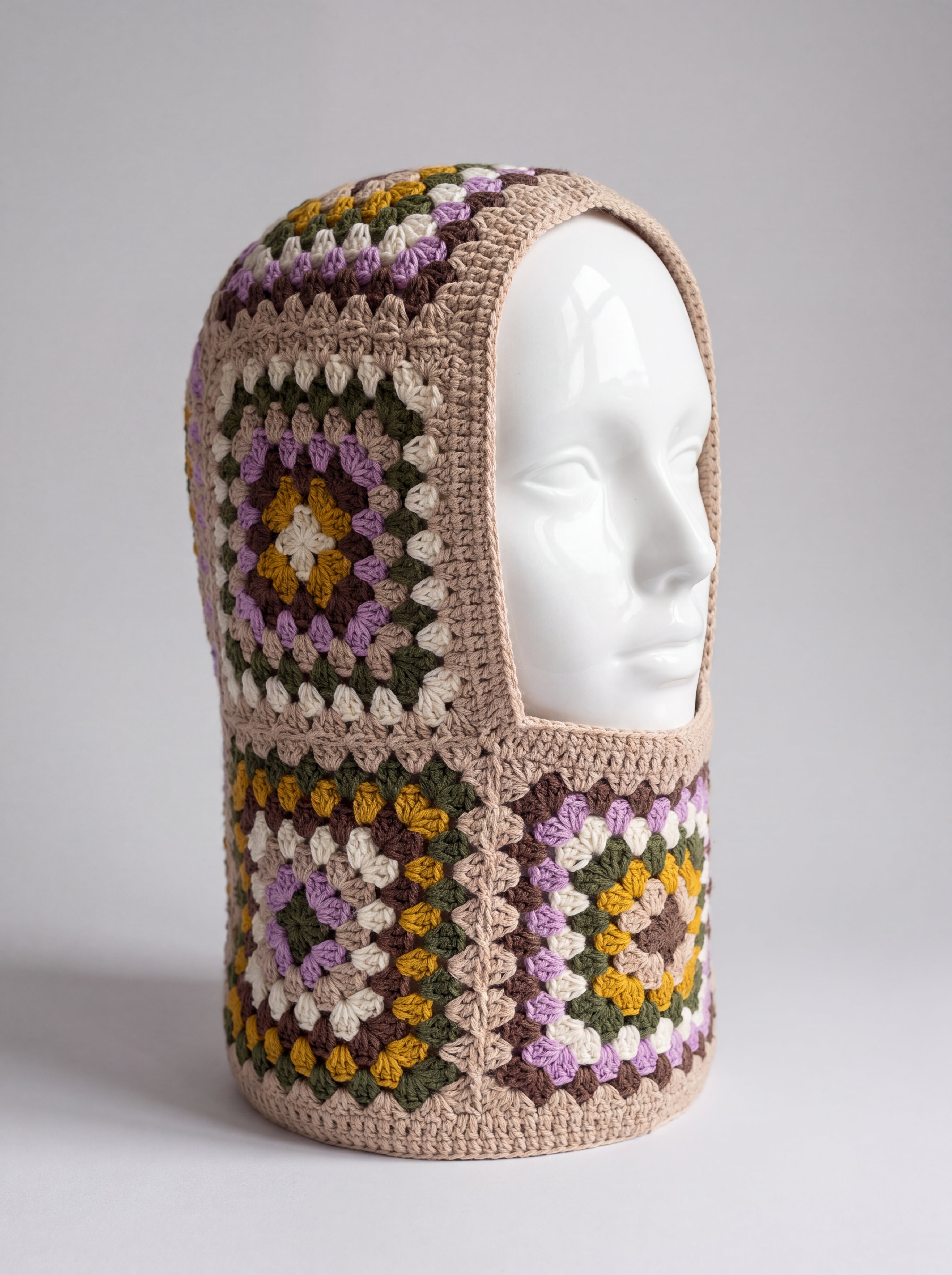 Sand and lilac granny square balaclava on a display head, open face and deep neck section — handmade by Ana Chic