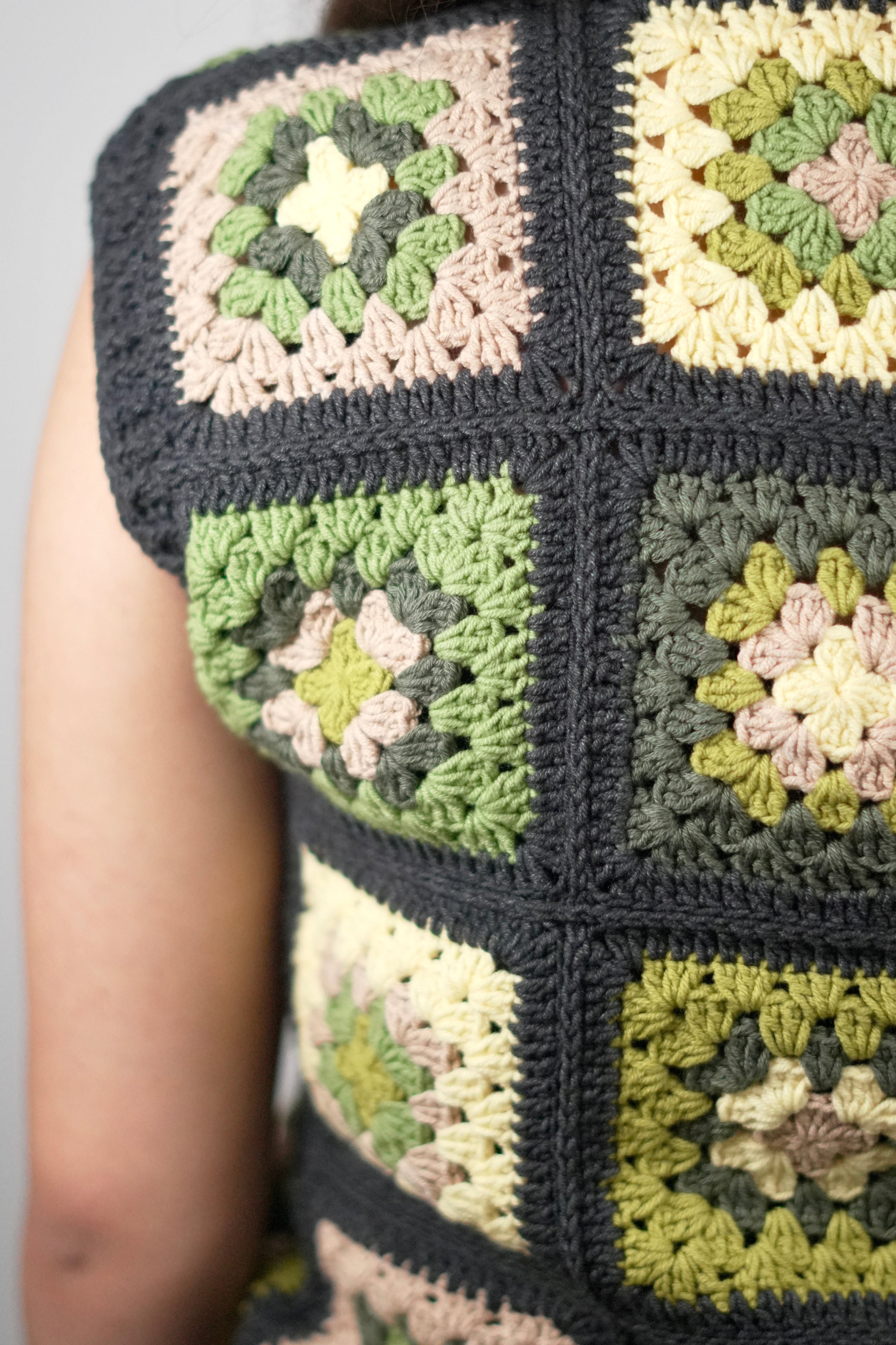 Close view of green and cream crochet squares framed in charcoal on the slipover — handmade by Ana Chic