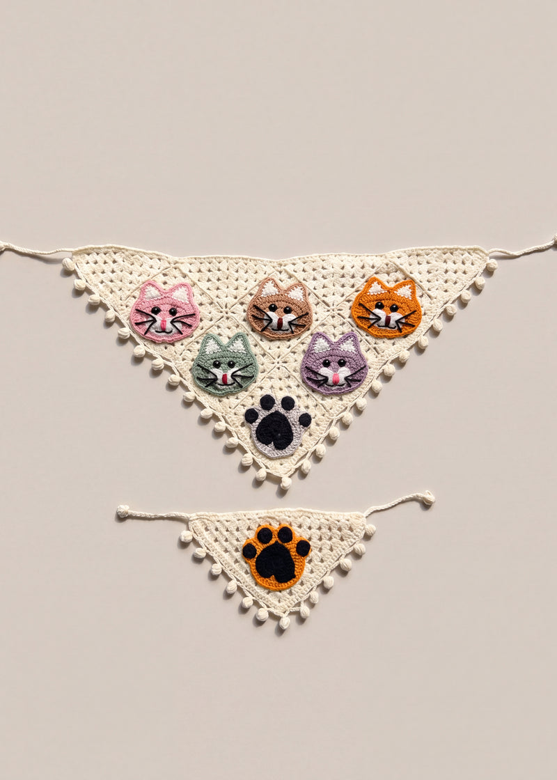 Cream crochet bandana set with five cat faces and a black paw, plus a small orange-paw cat bandana, laid flat — handmade by Ana Chic