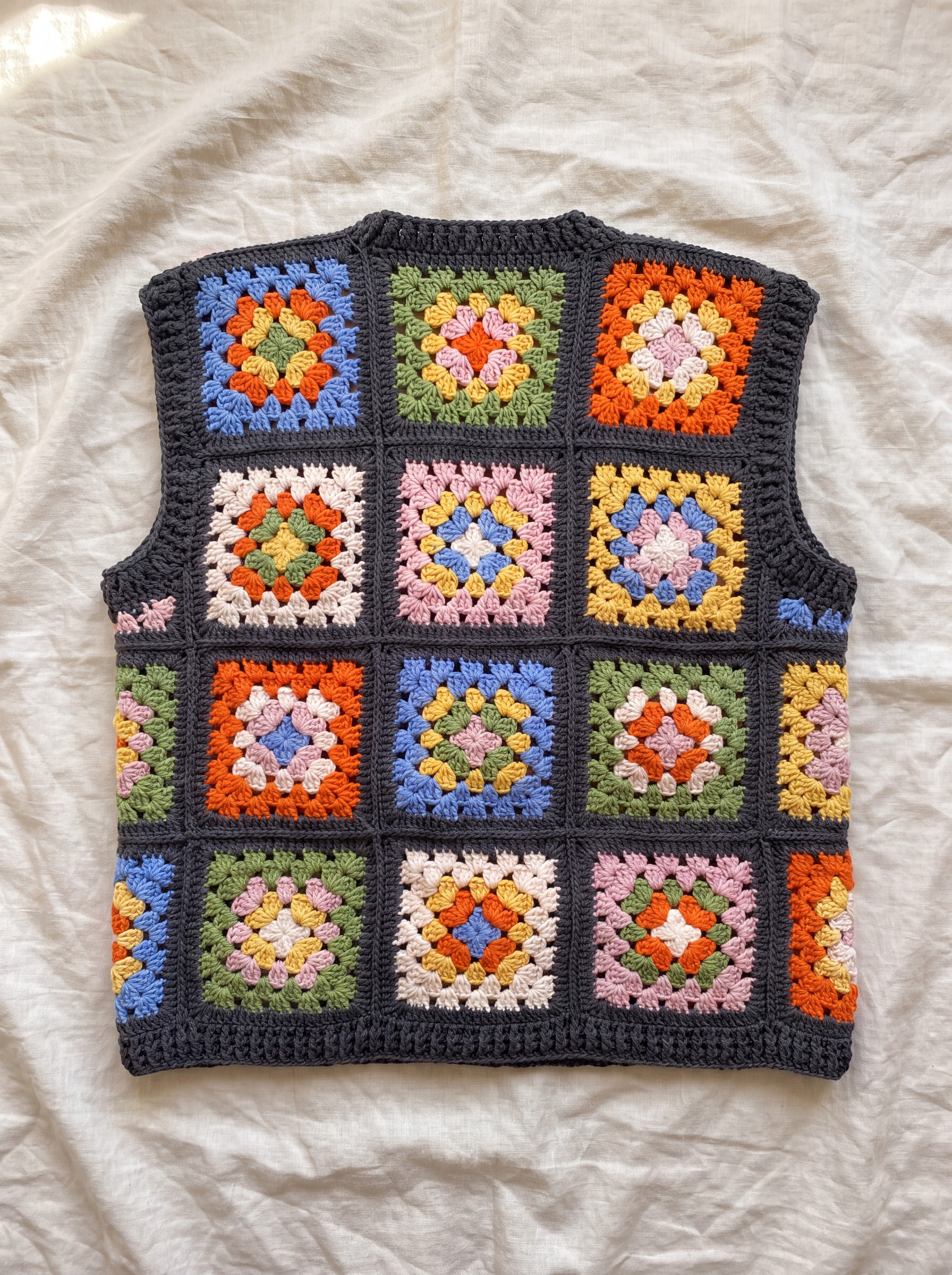 Multicolour granny square crochet vest, back, laid flat on linen