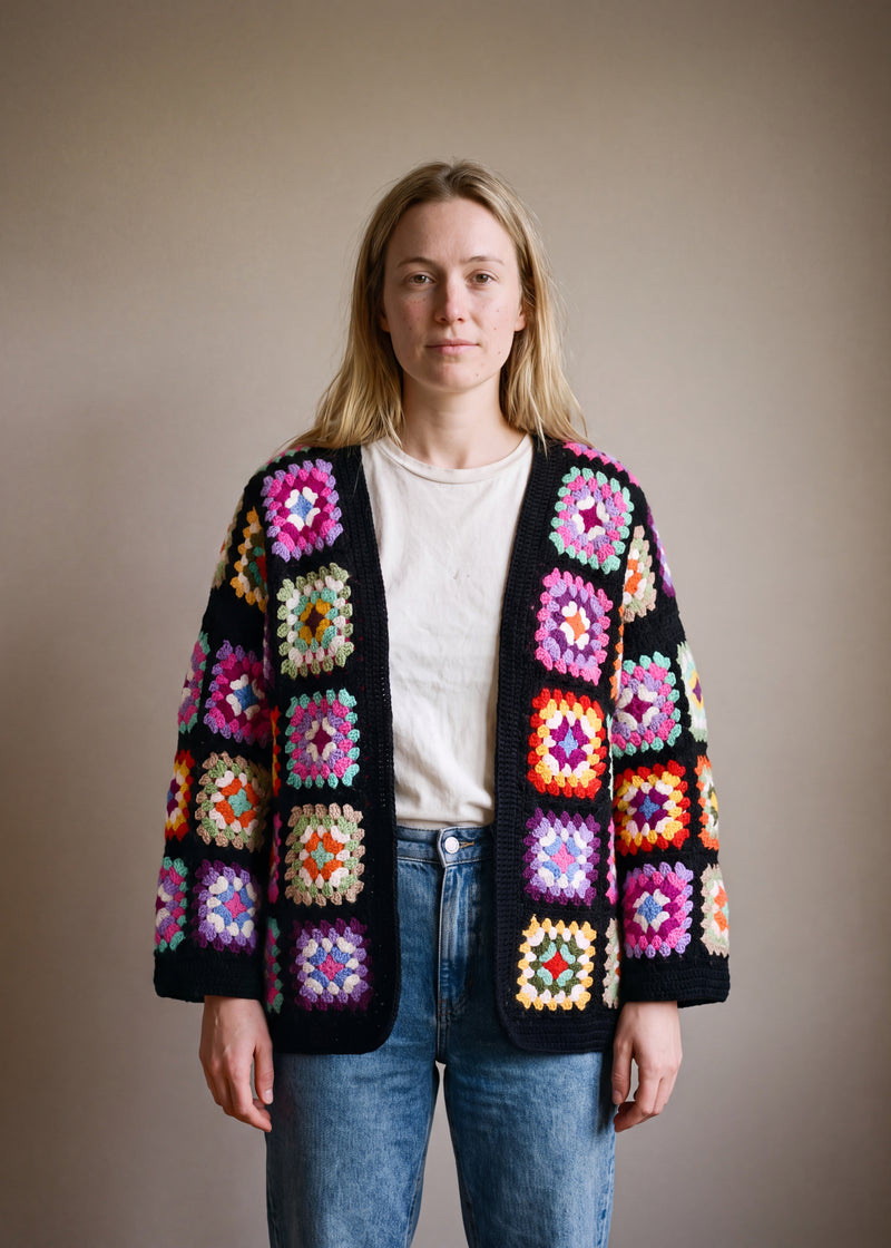 Black granny-square crochet cardigan worn open over a white round-neck top and blue jeans — handmade by Ana Chic
