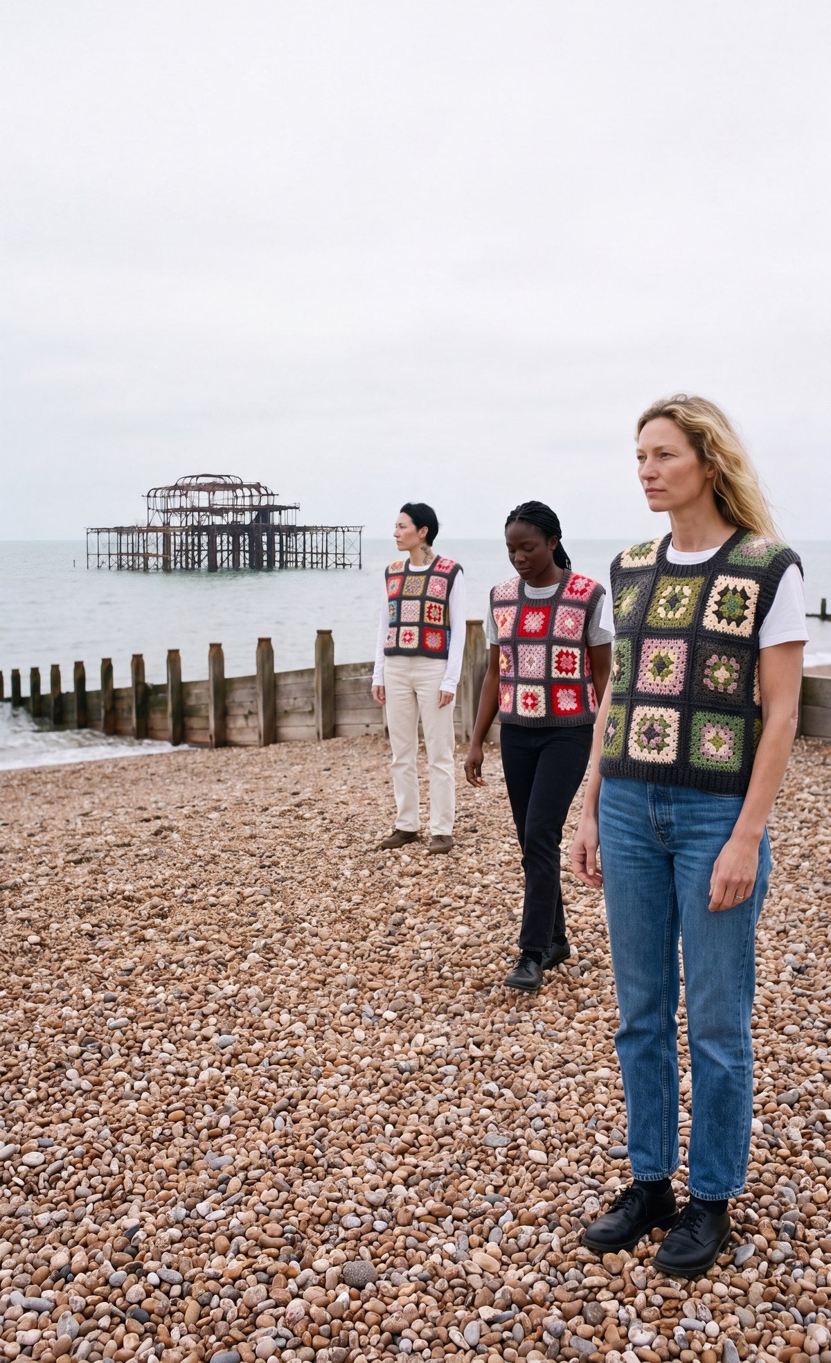 Three women on Brighton beach wearing hand-crocheted granny square vests