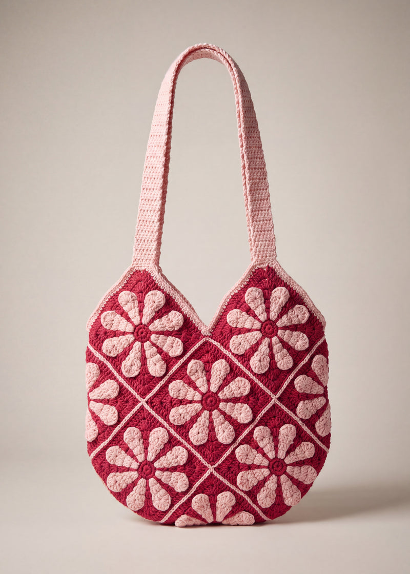 Front of the pink crochet shoulder bag with pale pink daisy granny squares on raspberry red and two wide straps — handmade by Ana Chic