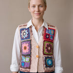Woman wearing the Bouquet Button Vest, a handmade granny square crochet vest, over a white shirt and dark jeans