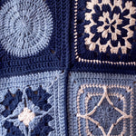 Close-up of four different hand-crocheted squares on the Sampler Cardigan in Navy, each a different motif design