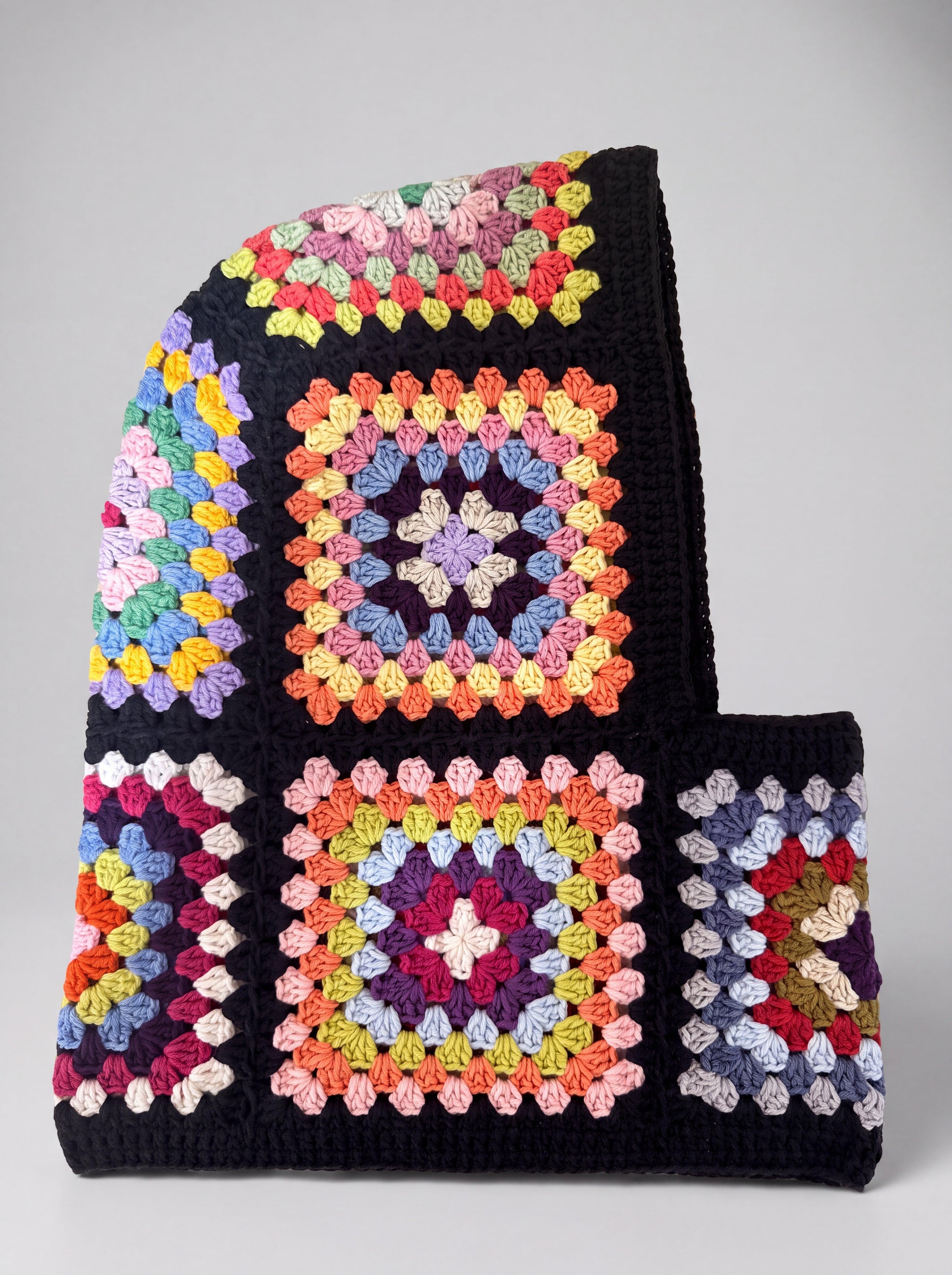 Black pastel granny square balaclava laid flat, side view of the hood — handmade by Ana Chic