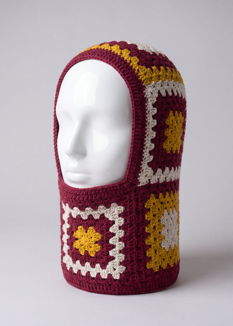 Burgundy and mustard granny square balaclava on a display head, open face and deep neck section — handmade by Ana Chic