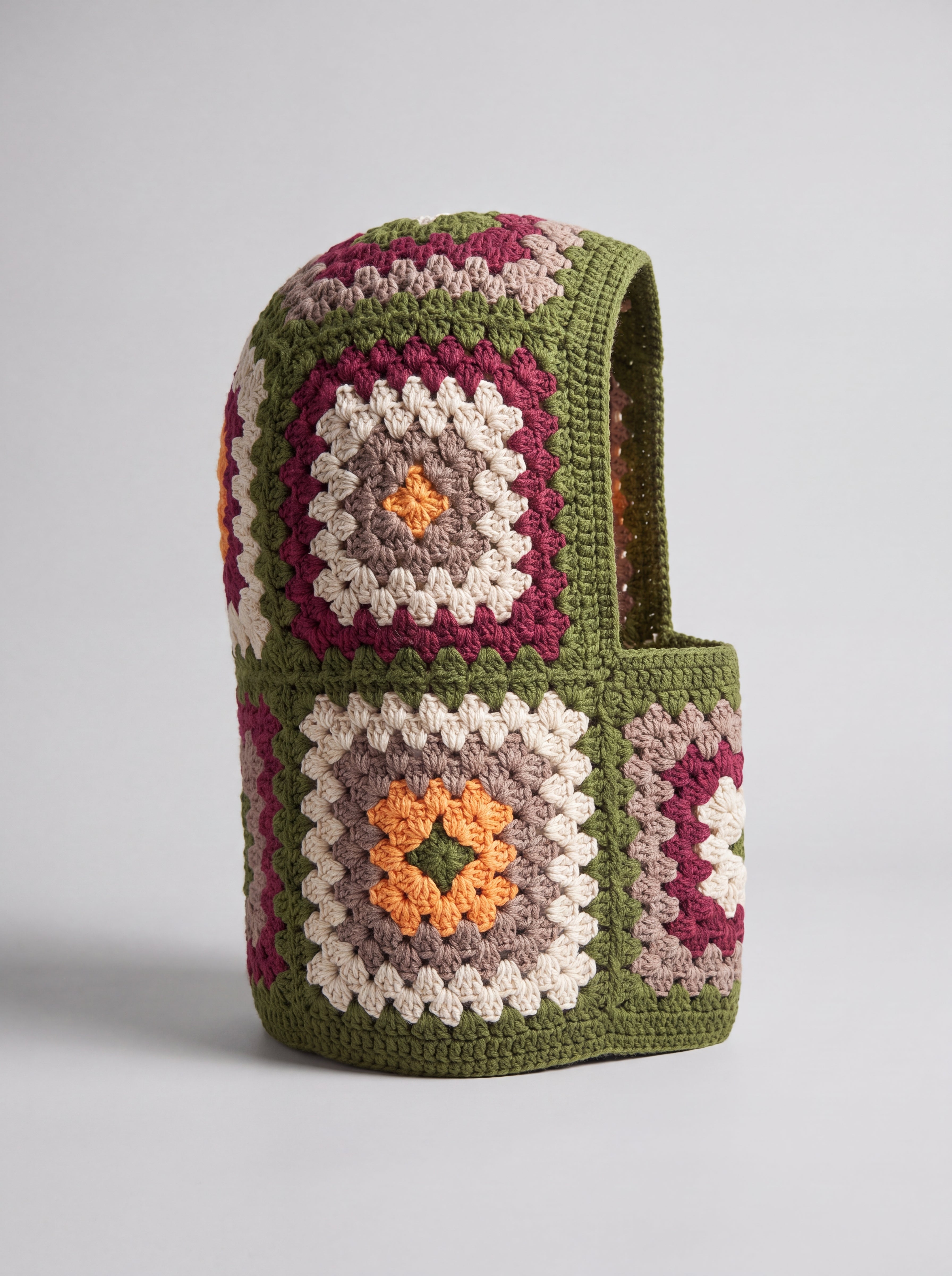 Olive green granny square balaclava standing on its own, back view of the hood — handmade by Ana Chic