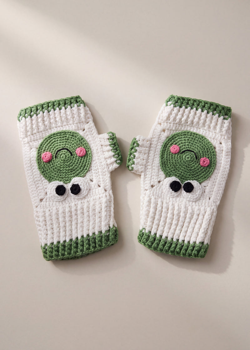 Pair of white crochet fingerless gloves with deep green ribbed cuffs, a green frog face on the back of each hand — handmade by Ana Chic