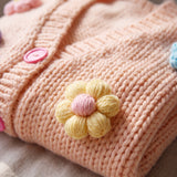 Detail of the Daisy Peach cardigan — a crocheted butter-yellow puff-stitch flower and pink buttons on peach chunky hand-knitted wool, handmade by Ana Chic