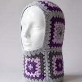 Grey and purple granny square balaclava on a display head, open face and deep neck section — handmade by Ana Chic