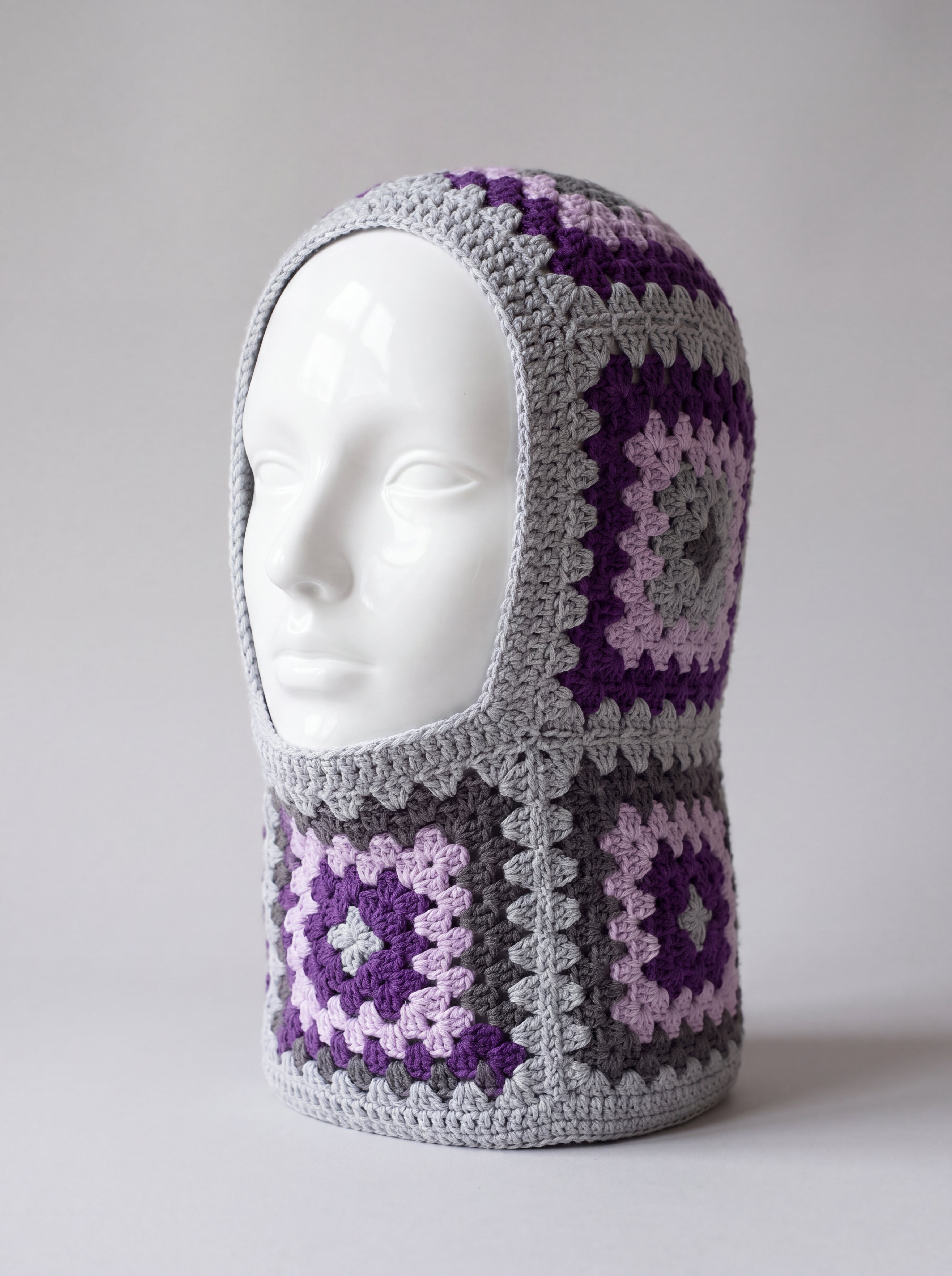 Grey and purple granny square balaclava on a display head, open face and deep neck section — handmade by Ana Chic