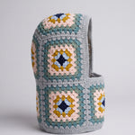 Teal and mustard granny square balaclava standing on its own, back view of the hood — handmade by Ana Chic