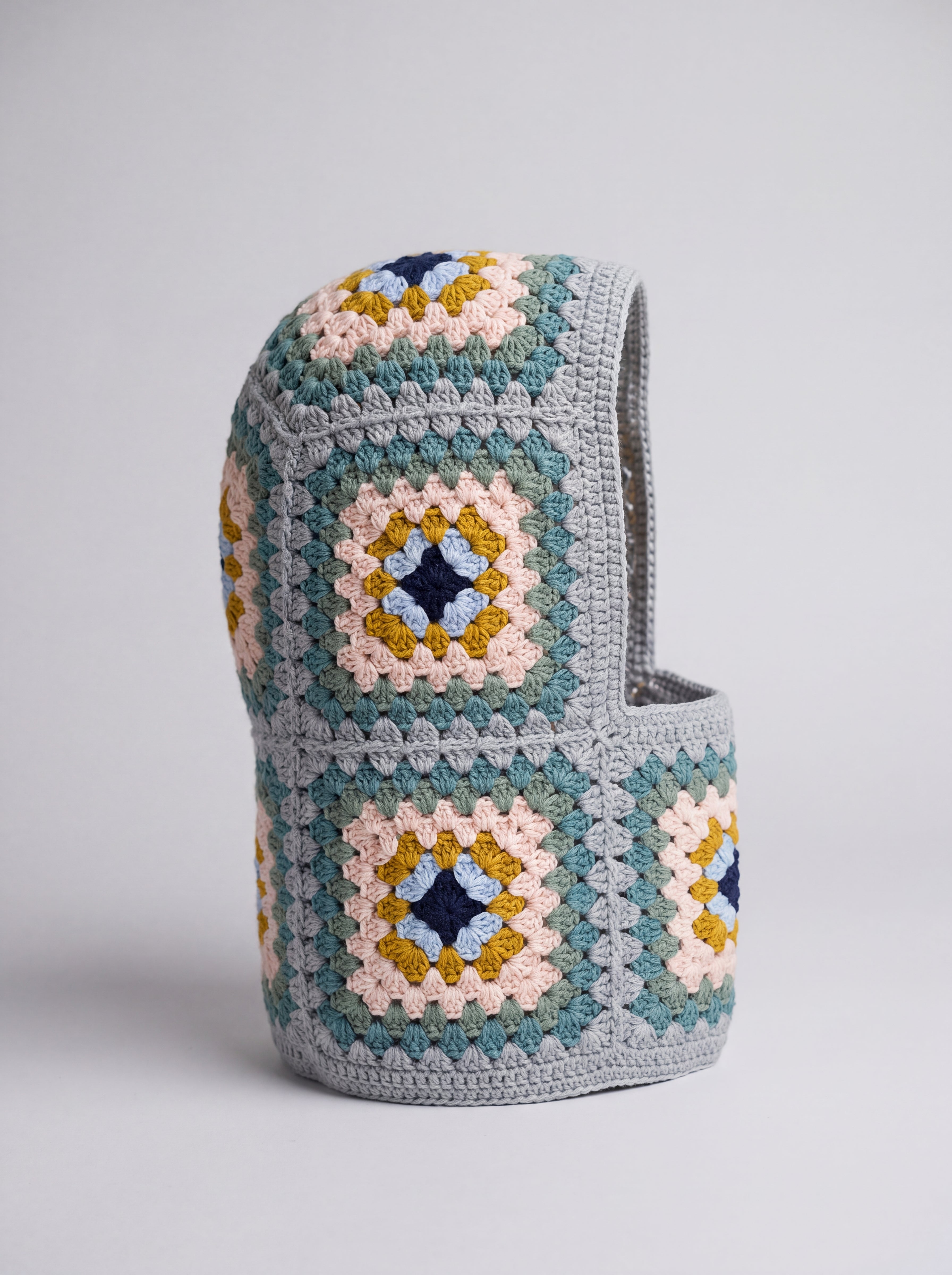 Teal and mustard granny square balaclava standing on its own, back view of the hood — handmade by Ana Chic
