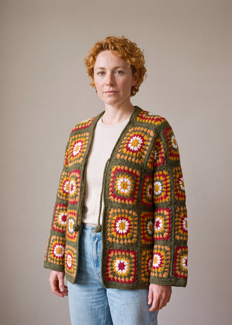 Green Boho Cardi worn by a model, olive green granny square crochet cardigan with crochet ties, open over a cream top