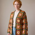 Green Boho Cardi worn by a model, olive green granny square crochet cardigan with crochet ties, open over a cream top