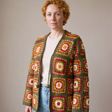Green Boho Cardi worn by a model, olive green granny square crochet cardigan with crochet ties, open over a cream top