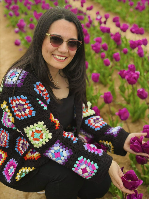 Customer in a colourful granny-square cardigan among tulips